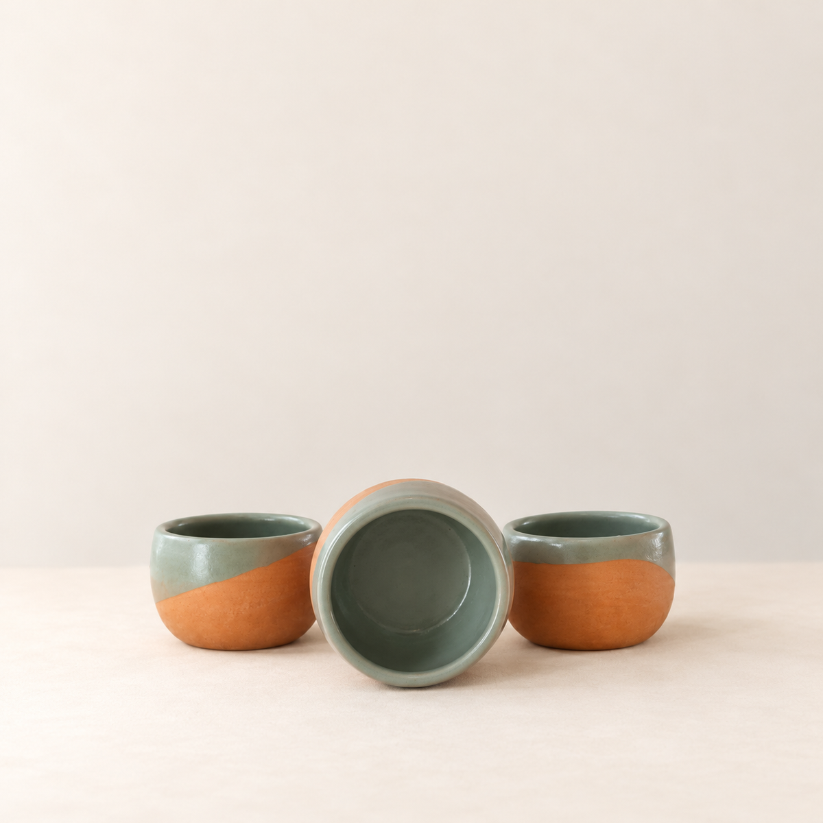 Three handmade Oaxacan clay cups by Rufina Ruiz Lopez, showing the green glazed interior